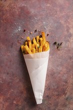 Fried French fries, in a paper bag, on an abstract background, no people, rustic