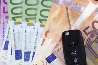 Euro banknotes and car keys as a symbol for car costs