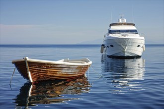 Concept for economic and social inequality showing small poor wooden fishing boat and luxury yacht