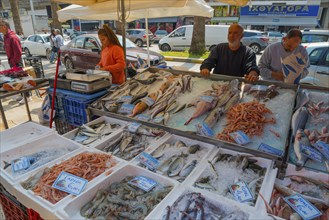 Fish market with a large selection of fish. A vendor serves customers in an urban environment,