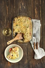 A baked casserole showcasing layers of cannelloni pasta, vegetables and melted cheese accompanied