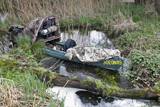 A canoe with camouflaged camera in a swamp, surrounded by vegetation and quiet nature, boat of a