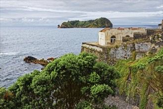 An old ruin on a rocky coast overlooking the sea and the small island and protected area of Ilhéu