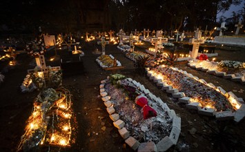 People from Christian community light candles and offer prayers on the grave of their relative