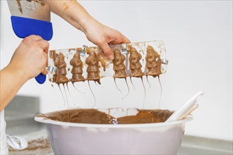 Two hands holding a chocolate mould over a large bowl, Christmas baking, Black Forest, Germany,