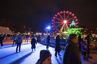 Ice skaters in front of the Neptune Fountain and a Ferris wheel at the Christmas market on