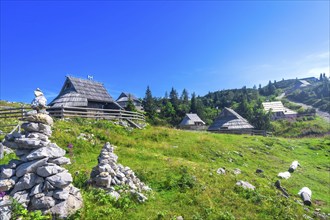 Charming wooden houses nestle on the vibrant slopes of velika planina, slovenia, creating a