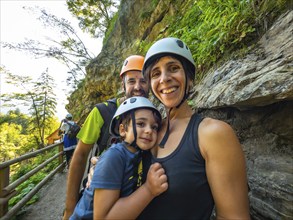 Family enjoying a hike through the scenic vintgar gorge near bled, slovenia, wearing helmets for