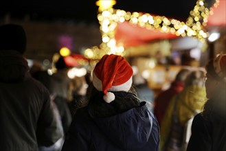 Person with a red cap at an illuminated Christmas market at night, Cologne, North Rhine-Westphalia,