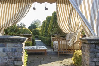 Modern gazebo in cottage garden with natural stone path and topiary. Modern landscape design