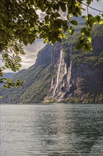 The majestic Seven Sisters waterfall flows down a forested mountain into the tranquil Gairanger