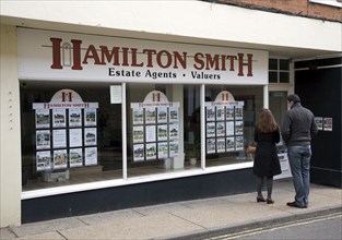 Young couple looking in estate agent shop window Woodbridge, Suffolk, England, UK