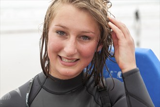 Teenage girl with wet face and hair close up portrait wet after swimming outdoors, UK -model