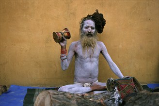 Hindu ascetic, sadhu from the naga sect, Nepal. His body is covered with ashes, he is playing