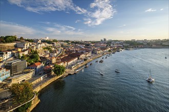 View of Vila Nova de Gaia city and Douro river with tourist boats on sunset. Porto, Portugal,