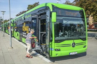 Elderly woman boards an electric bus in Ystad, Skåne County, Sweden, Scandinavia, Europe