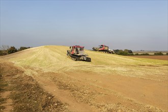 Piston Bully tracked bulldozer vehicles building silage clamp of sweetcorn maize in field stored