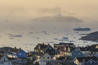 Houses in the fog in front of icebergs and ice floes, summer, midnight sun, Jakobshavn glacier and