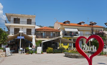 A lively town square with buildings and a large red heart in the centre, Sarti, Sithonia,