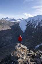 Mountaineer standing on a rock, surrounded by an impressive mountain landscape with snow-covered