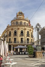 A historic building with a tower and clock, surrounded by people and street cafés, Jerez