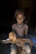 Himba girl with a goat in her hut, Ohandungu, Kunene Region, Kaokoveld, Namibia, Africa