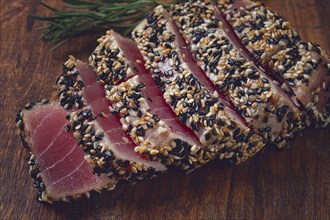 Fillet of red tuna meat, fried in sesame seeds, homemade, close-up, no people, on a wooden