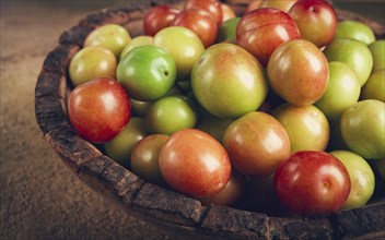 Cherry plum tkemali, fruit, plum variety, in a wooden plate, Georgian cuisine, top view, no people