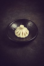 One khinkali, on a black plate, top view, cooking concept, Georgian cuisine