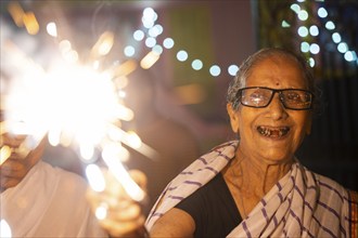 An elderly woman of Pramod Talukdar Memorial Old Age Home burn sparkler crackersas she celebrate