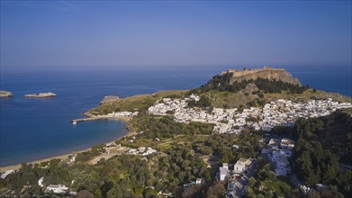 Drone shot, Lindos, Acropolis of Lindos, late afternoon light, view of a village with a fortress on