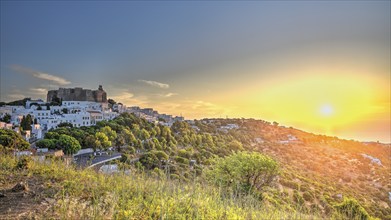 View of a castle and a white village on a hill at sunset, surrounded by green nature, Chora, main