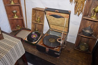 Close-up of an antique record player with records and decorative golden ornaments on a wooden