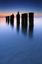 Stone pyramids on old groynes with algae in the water on the beach of the Baltic Sea, long exposure