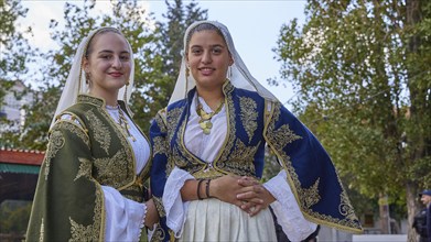 Women in traditional Cretan dress, surrounded by lush greenery, at a ceremony, Visit of Federal