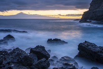 Before sunrise on the beach at San Marcos. Rocks and sea. Tenerife and the Teide in the background.