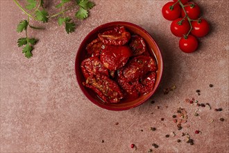 Dried tomatoes, in a bowl, top view, on a brown background