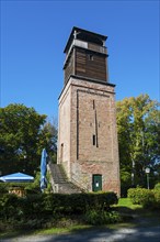 Old brick watchtower surrounded by trees under a clear sky, observation tower Hildesheimer Wald,