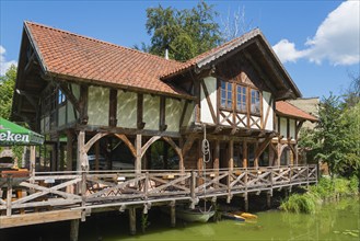 Half-timbered house with terrace by the water, surrounded by green nature and blue sky, Restaurant