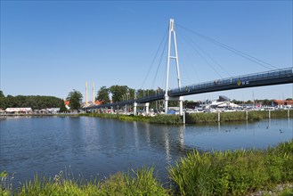 A modern bridge spans the water, surrounded by natural and urban elements, harbour and pier,