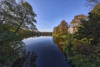 Mill pond with trees against blue sky, reflections on the water surface, Hanseatic city of Lübeck,