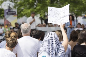 A visitor with a Palestinian scarf holds a piece of paper with the inscription Grundgesetz Says No