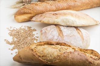 Different kinds of fresh baked bread on a white wooden background. side view, close up