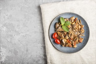 Fried oyster mushrooms with tomatoes on gray concrete background. Top view, copy space