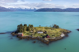 Aerial view of typical red houses on an island in the Hardangerfjord, mountain range in the back,