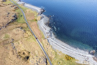 Aerial view of coast at Loch na Keal, coastal road and lonely red car on single track road, Isle of