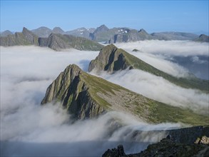 View over cloud covered mountain range at Mt. Husfjell, view towards fjord Bergsfjorden, Senja