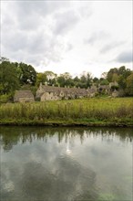 Famous Cotswold buildings at Arlington Row viewed from River Colne, Bibury, Gloucestershire,