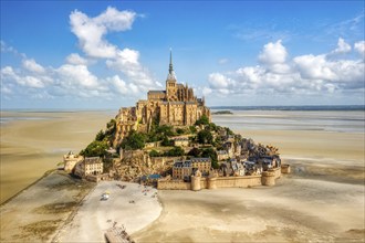 Gothic abbey on a sandy island, surmounted by a tower, in bright daylight, Le Mont-Saint-Michel