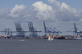 Sailing boat in front of container ships moored at the port of Felixstowe, Suffolk, England, United